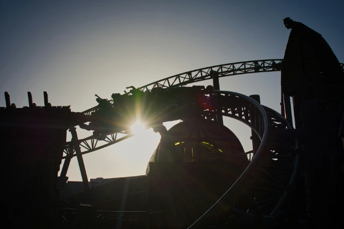 A roller coaster train in silhouette against a bright low sun